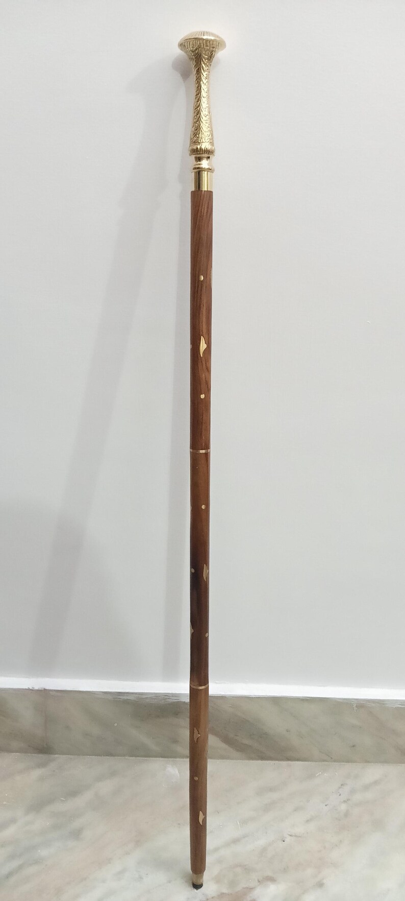 Peut inclure: Canne de marche d&eacute;corative avec une poign&eacute;e et des accents dor&eacute;s. Le f&ucirc;t est en bois brun fonc&eacute; avec des d&eacute;tails incrust&eacute;s dor&eacute;s. La canne mesure environ 91 cm de long.