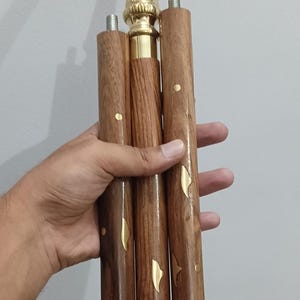 Peut inclure: Canne de marche en bois avec une poign&eacute;e et des accents d&eacute;coratifs en laiton. La canne est marron avec des ornements en laiton et un embout en caoutchouc. La poign&eacute;e a un design orn&eacute; et textur&eacute;.