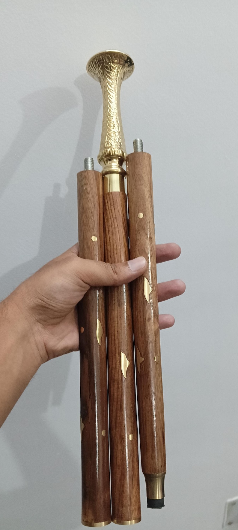 Peut inclure: Canne de marche en bois avec une poign&eacute;e et des accents d&eacute;coratifs en laiton. La canne est marron avec des ornements en laiton et un embout en caoutchouc. La poign&eacute;e a un design orn&eacute; et textur&eacute;.