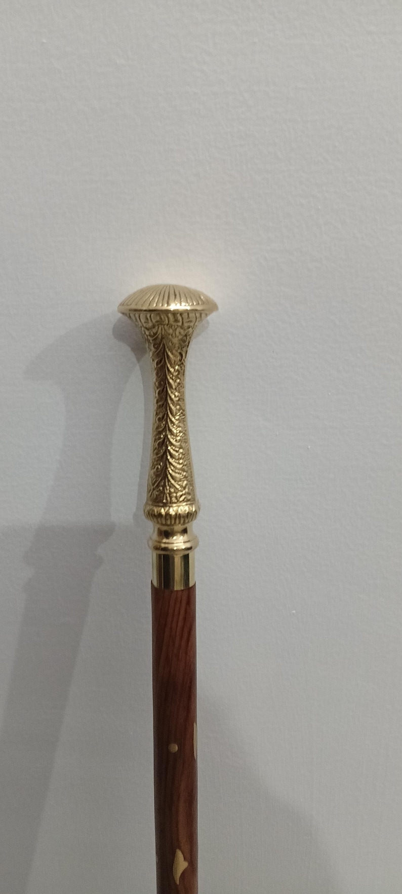 Peut inclure: Canne de marche d&eacute;corative avec une poign&eacute;e dor&eacute;e orn&eacute;e et un f&ucirc;t en bois brun fonc&eacute;. La poign&eacute;e pr&eacute;sente un dessus arrondi et des sculptures d&eacute;taill&eacute;es. La tige a des incrustations.
