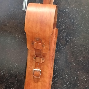 Peut inclure: Un &eacute;tui en cuir marron fait &agrave; la main avec une fermeture &agrave; boucle et une poign&eacute;e. L'&eacute;tui est con&ccedil;u pour contenir un objet long et fin, peut-&ecirc;tre un outil ou un ustensile. Une tige m&eacute;tallique argent&eacute;e est &agrave; c&ocirc;t&eacute; de l'&eacute;tui.