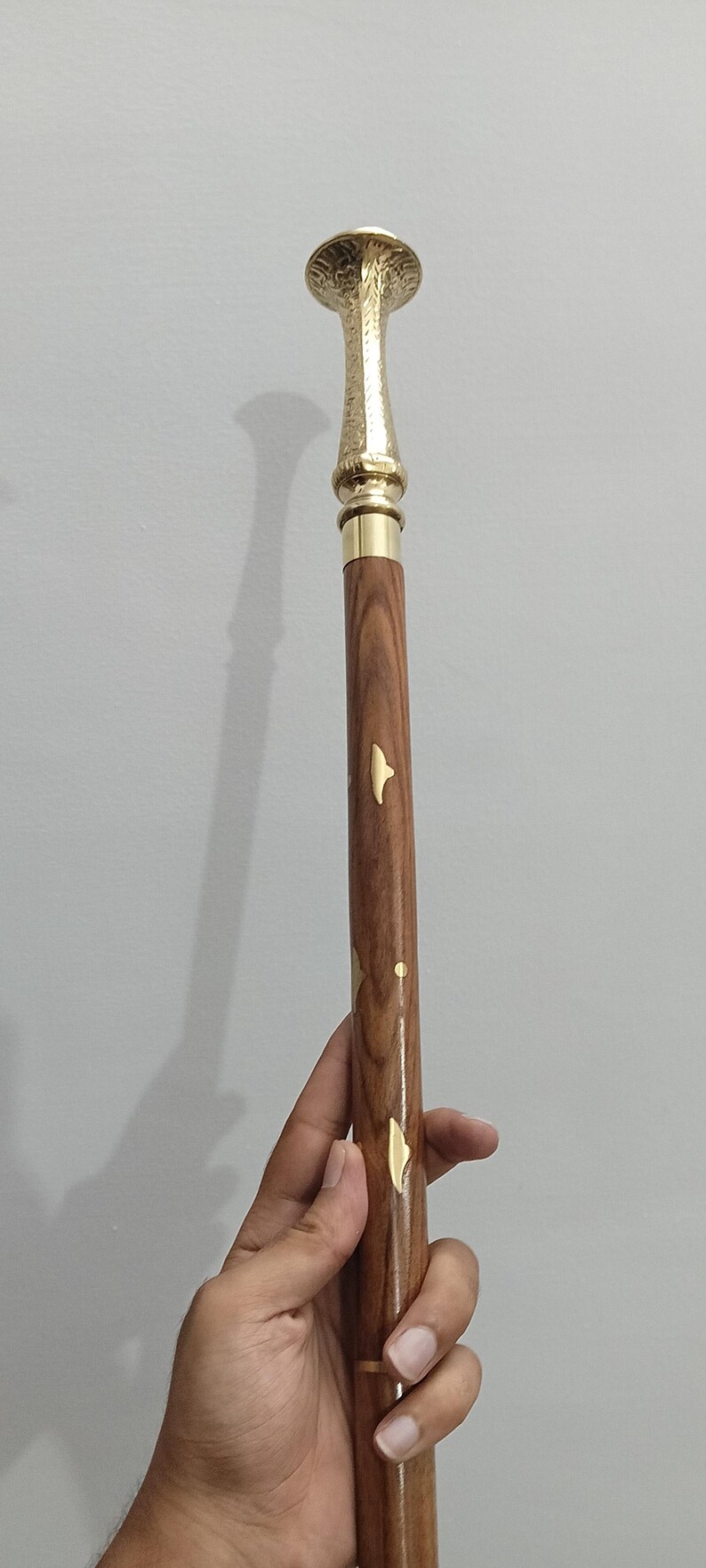 Peut inclure: Canne de marche d&eacute;corative avec une poign&eacute;e et des accents dor&eacute;s. La tige est en bois avec des incrustations dor&eacute;es en forme de feuilles. La poign&eacute;e a un design textur&eacute;. La canne mesure environ 91 cm de long.