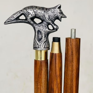 Puede incluir: Bastón decorativo con un mango de cabeza de lobo plateado. El bastón tiene un eje de madera con detalles en latón. El bastón mide aproximadamente 91 cm de largo.