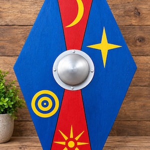 May include: A hexagonal wooden shield featuring a central silver metal boss. The surface is divided into red and blue sections, decorated with yellow painted symbols including a crescent moon, a four-pointed star, a target, and a sunburst.
