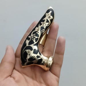Pu&ograve; includere: Un oggetto curvo color oro con una parte superiore nera a motivi floreali. L'oggetto ha una base ad anello ed &egrave; tenuto in mano. Il design presenta accenti floreali color oro su sfondo nero.