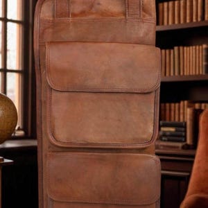 Può includere: Una borsa tote in pelle marrone con due tasche frontali e un manico superiore. La parola "Chris" è impressa sul davanti. La borsa è realizzata in pelle ricca e strutturata.