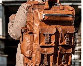 May include: A large, brown leather backpack with multiple pockets and compartments. The backpack has a top handle, a zippered front pocket, and several smaller pockets with buckle closures. The leather appears to be distressed, giving it a vintage look.