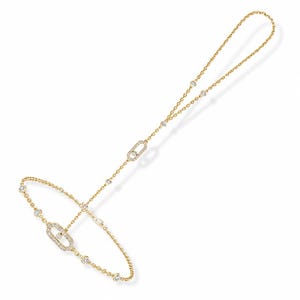 May include: A gold hand chain bracelet featuring a delicate chain design with two oval-shaped links encrusted with small clear stones. The piece includes additional round bezel-set stones spaced along the chain, connecting a ring loop to a wrist band.