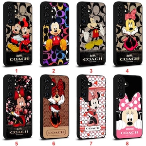 Op de afbeelding: Acht telefoonhoesjes met ontwerpen van Mickey en Minnie Mouse. Elke hoes heeft een zwarte rand en een ander ontwerp, inclusief het Coach-logo. De hoesjes tonen verschillende poses en outfits van de beroemde stripfiguren.