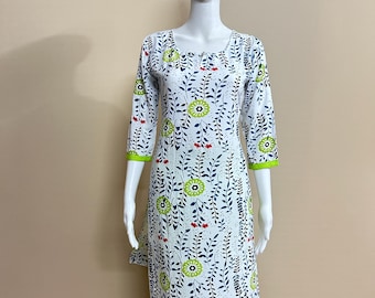 May include: White tunic and pants set with a floral pattern. The tunic has a scoop neck and three-quarter sleeves with green trim. The floral design includes green and blue leaves with red accents. The pants are a bright green color.