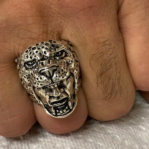 May include: A silver ring with a detailed design of a snarling leopard's head.