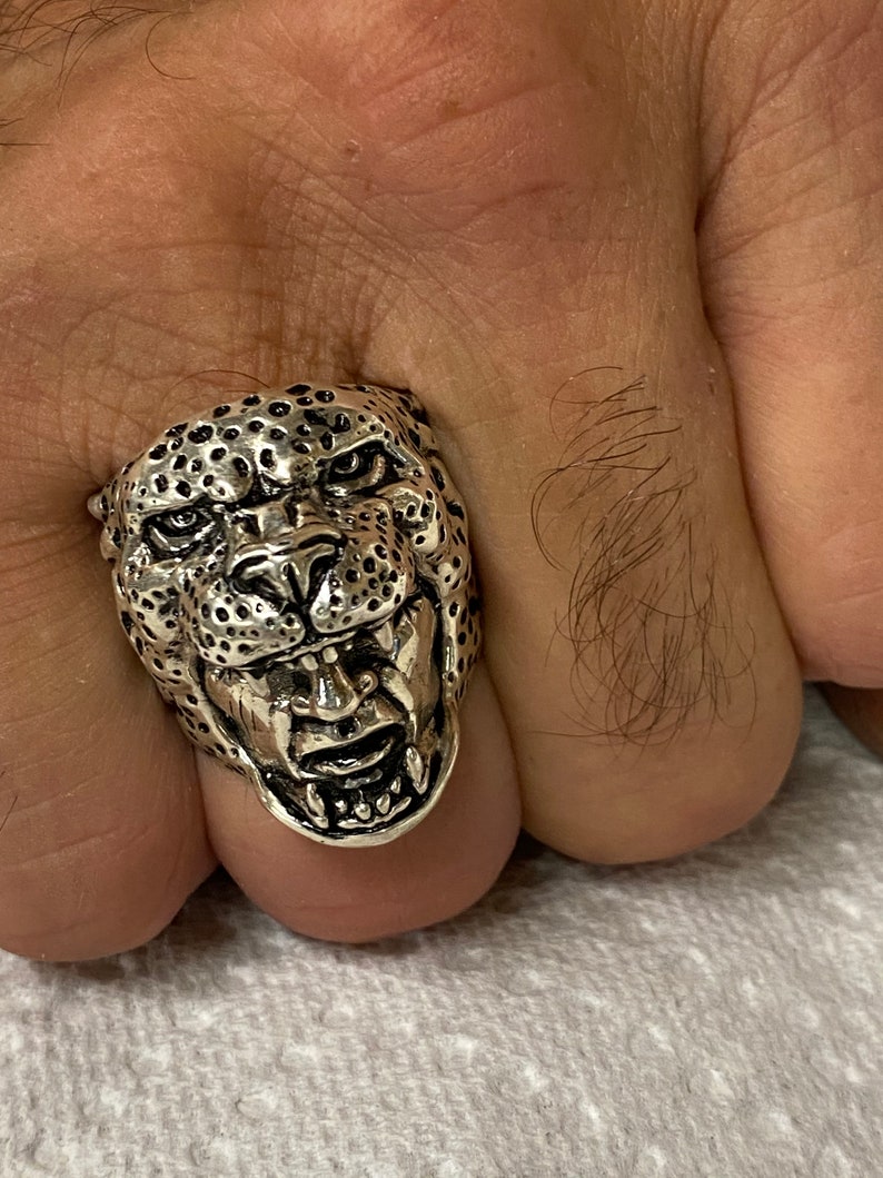 May include: A silver ring with a detailed design of a snarling leopard's head.