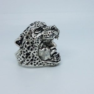 May include: A silver ring with a detailed design of a leopard's head. The leopard's mouth is open, revealing sharp teeth.