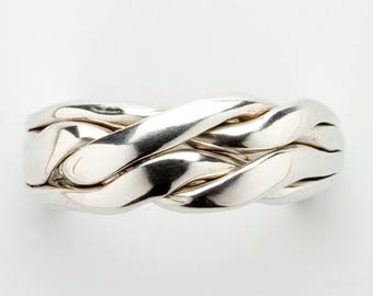 May include: A silver puzzle ring with a braided design. The ring is made of multiple interlocking pieces.