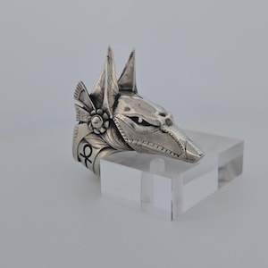 May include: Silver ring featuring a detailed Anubis head design with an ankh symbol on the side.