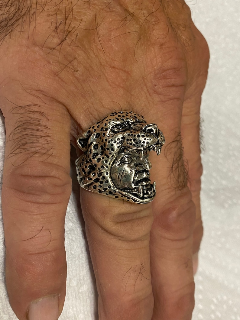 May include: A silver ring with a detailed design of a leopard's head with an open mouth.