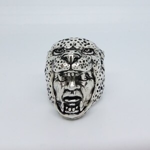 May include: A silver ring with a detailed design of a leopard's face. The ring features a realistic depiction of the animal's features, including its spots, eyes, and teeth.
