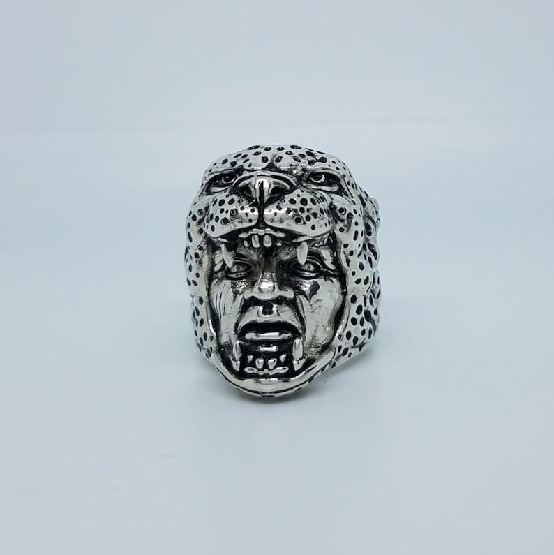 May include: A silver ring with a detailed design of a snarling jaguar head.