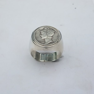 K&ouml;nnte beinhalten: Silberring mit einem 1945 Mercury Dime, der oben eingefasst ist. Der Ring ist ein schlichtes Band mit einer glatten Oberfl&auml;che.