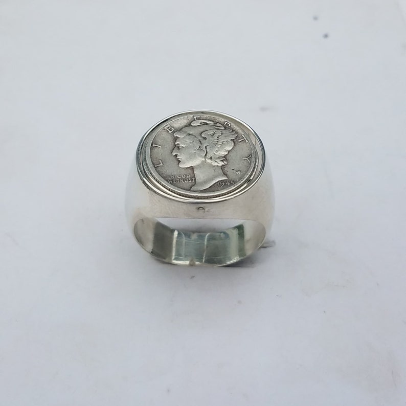 K&ouml;nnte beinhalten: Silberring mit einem 1945 Mercury Dime, der oben eingefasst ist. Der Ring ist ein schlichtes Band mit einer glatten Oberfl&auml;che.