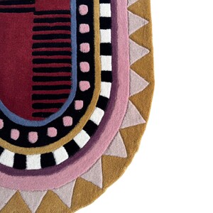 K&ouml;nnte beinhalten: Ein farbenfroher, abstrakter Teppich mit halbkreisf&ouml;rmiger Form. Der Teppich zeigt eine Kombination aus geometrischen Mustern und Formen in Rot-, Schwarz-, Rosa-, Blau-, Wei&szlig;- und Goldt&ouml;nen. Das Design umfasst Streifen, Punkte und Dreiecke.