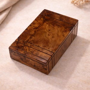 May include: A rectangular wooden box with a dark brown finish. The box has a detailed wood grain pattern and horizontal grooves on the lid. The box is likely for storage or display. The dimensions are in centimetres.