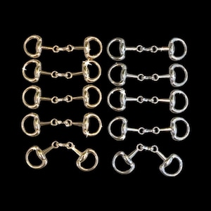 May include: An assortment of horse bits in gold and silver tones, arranged against a black background. The bits are of various styles, including snaffle and curb bits, and are designed for equestrian use. The image showcases the different designs and metal finishes.