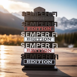 May include: A stack of black and red signs with the words "SEMPER FI EDITION" in white lettering. The signs are arranged in a vertical tower, with a wooden mountain backdrop.