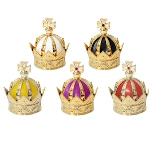 May include: Five decorative crown-shaped bottle stoppers. Each crown features a gold-colored base with intricate detailing and a colored top in white, black, yellow, purple, and red. A gold cross adorns the top of each crown.