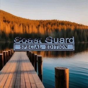 Könnte beinhalten: Eine malerische Seelandschaft mit einem Holzsteg, auf dem die Worte "Coast Guard SPECIAL EDITION" in Chrombuchstaben stehen. Der Hintergrund zeigt einen Wald und einen Sonnenuntergang, was eine ruhige Atmosphäre schafft.