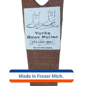 May include: Brown boot puller with a textured surface and a Y-shaped design. The puller has a white label with the text "Yorks Boot Puller" and "Fits Every Boot". The bottom of the puller has the text "Made in Fraser Mich."