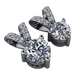 Può includere: Due orecchini pendenti color argento con grandi pietre preziose rotonde e trasparenti. Ogni orecchino ha un alone di pietre preziose chiare più piccole attorno alla pietra principale e sulla parte superiore curva. Su sfondo bianco.