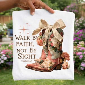 May include: White decorative towel featuring a pair of pink and turquoise cowboy boots adorned with floral patterns and a large beige bow. The text "WALK BY FAITH, NOT BY SIGHT" is printed on the towel, along with the Bible verse 2 Corinthians 5:7.