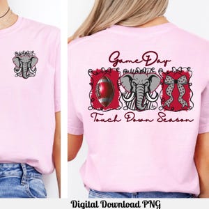 Puede incluir: Camiseta rosa claro con un gráfico de elefante gris y la frase "Game Day Touch Down Season". La parte trasera de la camiseta presenta un diseño de fútbol americano, elefante y lazo en rojo y gris.