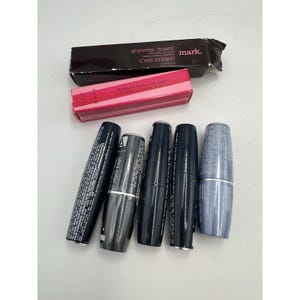 May include: A collection of cosmetics, including lip gloss and lip tint. The image shows a black box with the text "shimmer down!" and "c'est brillant!", a pink box with "ROLLER BALL LIP TINT", and several lip color tubes.