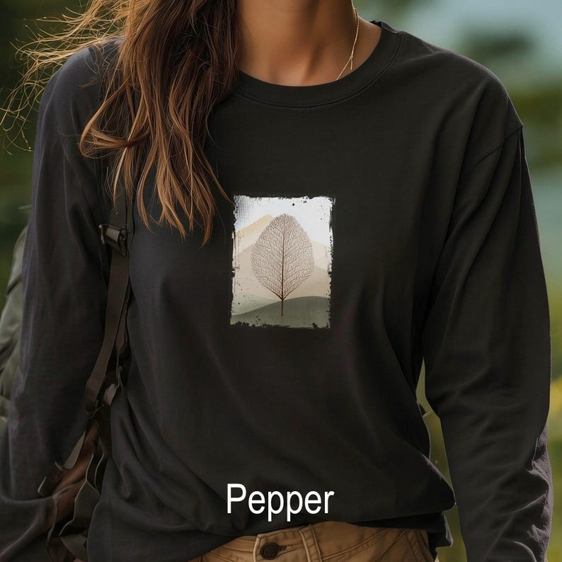 May include: A black long-sleeve shirt with a rectangular graphic of a leaf skeleton against a mountain landscape. The word "Pepper" is printed at the bottom of the shirt.