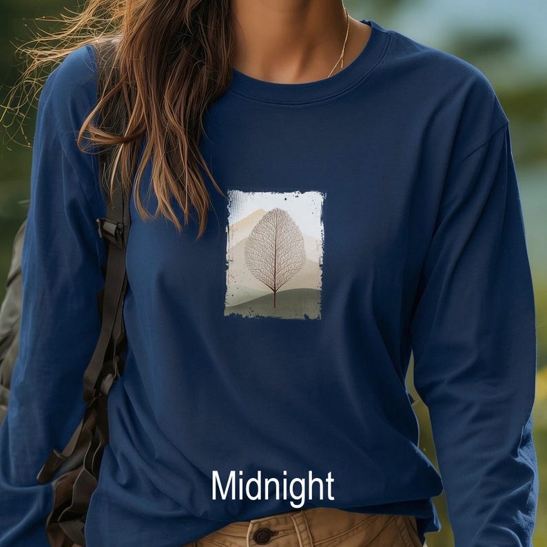 May include: A navy blue long-sleeve shirt with a rectangular graphic of a leaf and mountain scene. The word "Midnight" is printed at the bottom of the shirt in white. The shirt is made of a soft material.