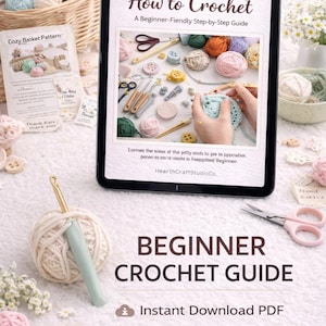 以下が含まれることがあります： タブレットには「How to Crochet」というタイトルの編み物ガイドが表示されています。画像には、毛糸玉、かぎ針、ハサミ、そして「BEGINNER CROCHET GUIDE」というテキストが含まれています。「Instant Download PDF」と「Learn Basic Stitches」というテキストも表示されています。
