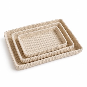 May include: A set of three nested rectangular trays in a light beige color, each featuring a textured, hand-crocheted surface with a consistent stitch pattern. The trays are stacked one inside the other, displaying a uniform design and structure.