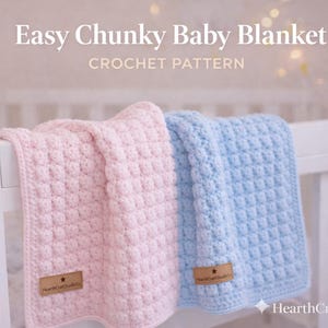 May include: A pink and a blue chunky baby blanket, crocheted with a textured stitch, are draped over a white cot. The blankets have a square pattern and a small brown tag with text. The image includes the text "Easy Chunky Baby Blanket CROCHET PATTERN".