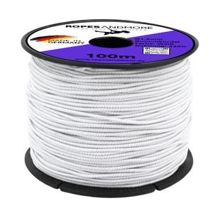 Puede incluir: Un carrete de cordón elástico blanco, etiquetado como "ROPESANDMORE" con "MADE IN GERMANY". El carrete es negro con una etiqueta morada y blanca, y el cordón mide 100 metros de largo. El cordón tiene 1,2 mm de diámetro.