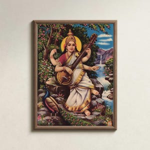 May include: A framed print depicting a seated figure playing a stringed instrument, surrounded by a peacock, flowers, and a waterfall. The figure wears a red top and white sari, with a golden halo. The artwork is set in a natural landscape.