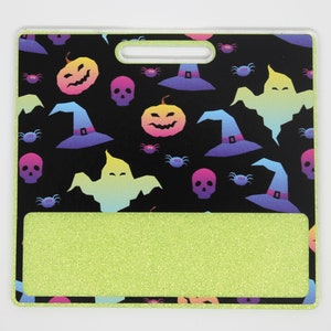 K&ouml;nnte beinhalten: Ein Ausweishalter zum Thema Halloween mit schwarzem Hintergrund und einem sich wiederholenden Muster aus bunten K&uuml;rbissen, Hexenh&uuml;ten, Geistern, Totenk&ouml;pfen und Spinnen. Der untere Bereich ist glitzernd limettengr&uuml;n und hat einen Griff.