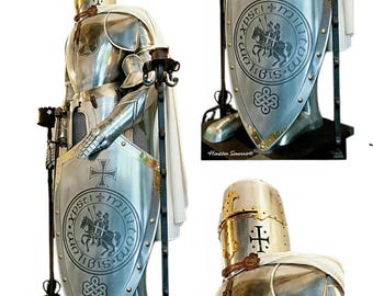 Puede incluir: Una armadura completa de caballero medieval, hecha de metal pulido. La armadura incluye un casco, peto y perneras, con una capa blanca. Los escudos presentan un diseño de cruz e inscripciones. Una pieza decorativa para entusiastas de la historia.