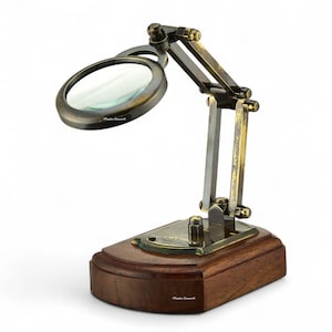 May include: A brass magnifying glass on an adjustable articulated arm mounted to a rectangular wooden base. The metal frame has a weathered finish, and a small plaque on the base features the text "W.F. Stanley & Co. London 1915".