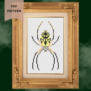 May include: A framed cross-stitch pattern featuring a yellow and black spider design. The artwork is displayed in a gold-colored ornate frame. The words "PDF PATTERN" are printed on a banner in the upper left corner.