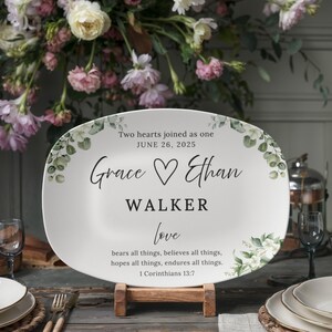 May include: White ceramic platter with floral accents and text. The platter reads "Two hearts joined as one, June 26, 2025, Grace ♡ Ethan WALKER love." The quote from 1 Corinthians 13:7 is also included.