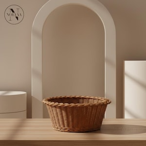 Peut inclure: Un panier tressé brun de forme ovale arrondie. Le panier est fait d'un matériau tissé serré et a une surface texturée. Il est posé sur une surface en bois brun clair.