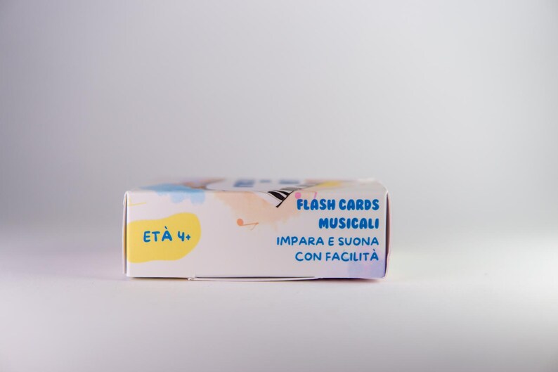K&ouml;nnte beinhalten: Eine rechteckige, wei&szlig;e Schachtel mit musikalischen Lernkarten. Sie zeigt farbenfrohe Illustrationen und italienischen Text, darunter "FLASH CARDS MUSICALI" und "ET&Agrave; 4+".