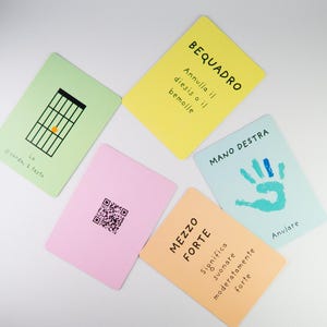 K&ouml;nnte beinhalten: Eine Sammlung farbenfroher Karteikarten mit musikalischen Begriffen und Symbolen. Die Karten sind in verschiedenen Farben gehalten, darunter Gr&uuml;n, Gelb, Rosa, Blau und Orange. Jede Karte enth&auml;lt Text und Illustrationen, wie z. B. ein Gitarrenakkorddiagramm und einen Handabdruck.